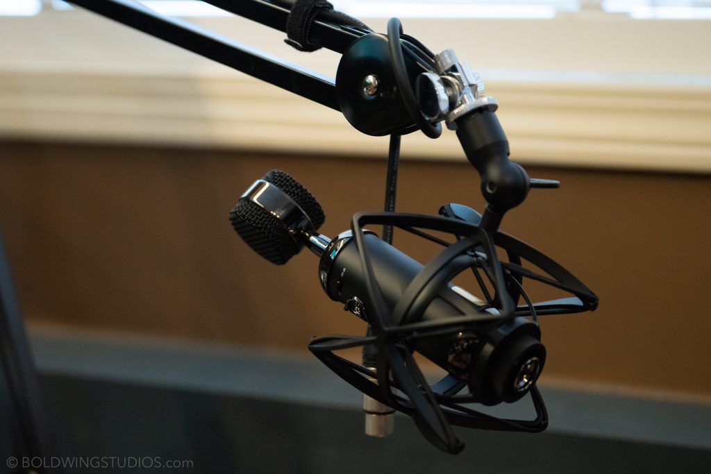 Black podcast microphone on a boom arm in the MediaHive studio